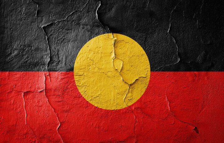 Image of the Australian Aboriginal Flag - it features a yellow circle representing the sun and giver of life, this is set against two colours split equally in half horizontally - black and red. Black is at the top, representing the Australian Aboriginal people, and Red on the bottom half, representing the Earth and the Red Ochre used in ceremony. 