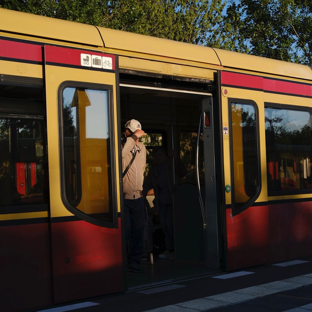 S-Bahn stopping and opening its doors revealing a person holding its cap