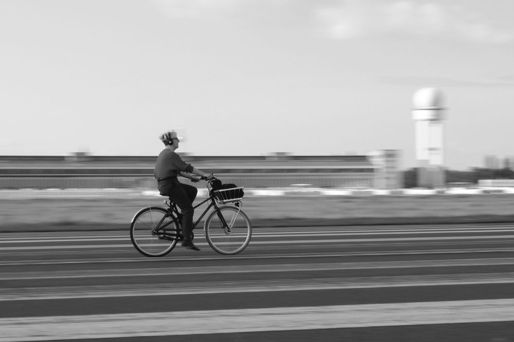 Eine fahrradfahrende Person auf dem Tempelhofer Feld in Schwarz-Weiß. 