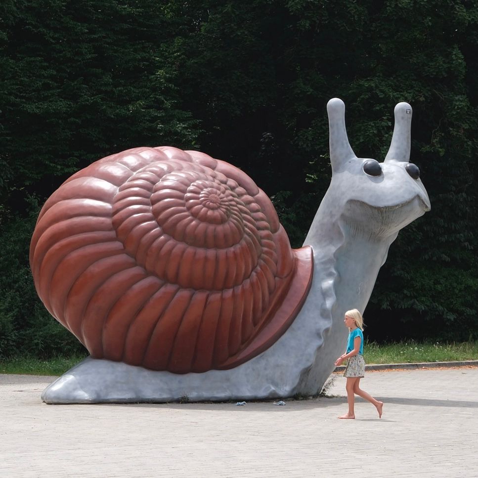 Oversized snail statue with a child running around it. 