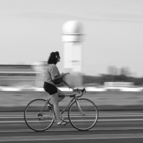 A person riding a bicycle in front of the tower of Tempelhofer Feld. 