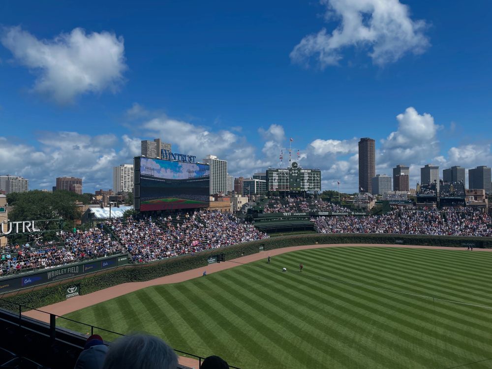 Picture of left field bleachers, giant video board and scoreboard at Wrigley Field. 
