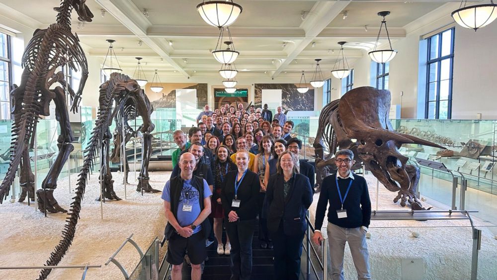 The Non-Clinical Tomography Users Research Network standing all together in the dinosaur hall at the American Museum of Natural History 