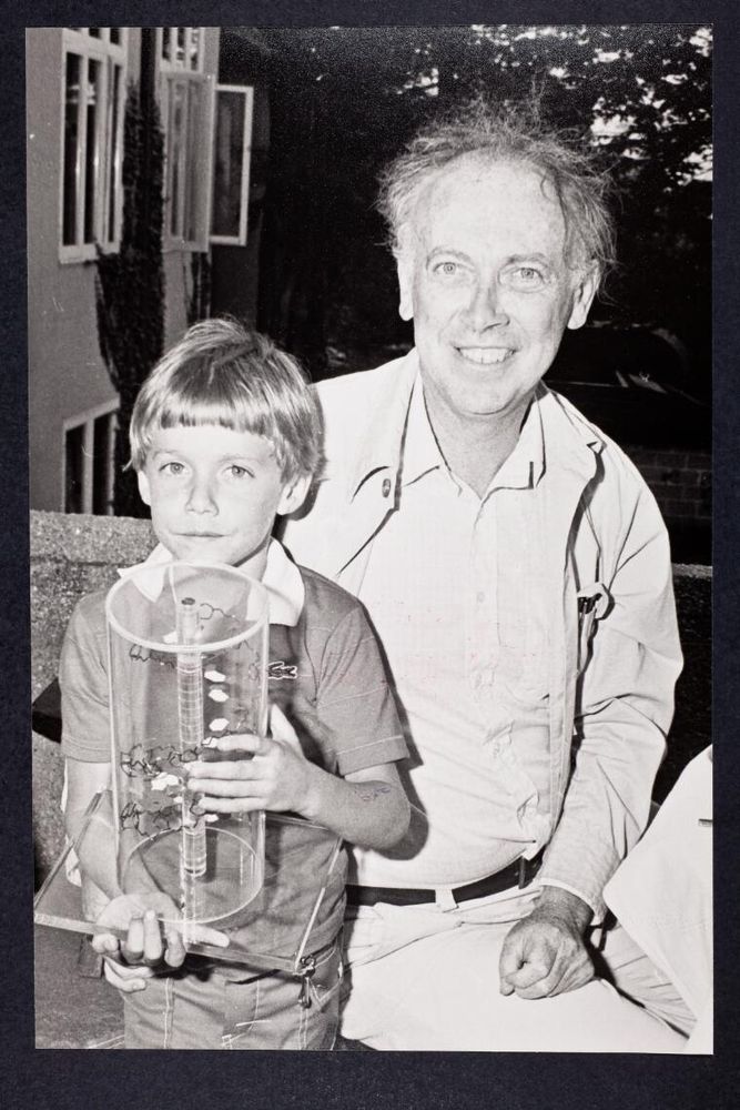 James Watson with his younger son, Duncan, then 6. The boy is holding a historic model of the double helix. Watson is smiling. Courtesy CSHL Archives