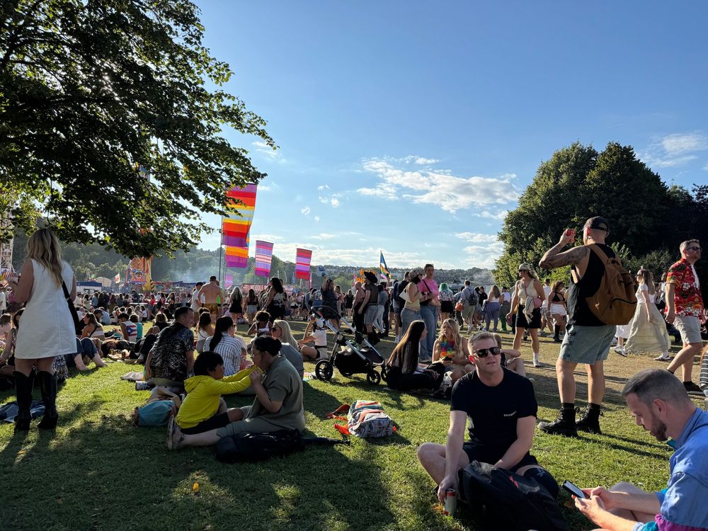 Photo of the park with lots of people sat on the green grass.