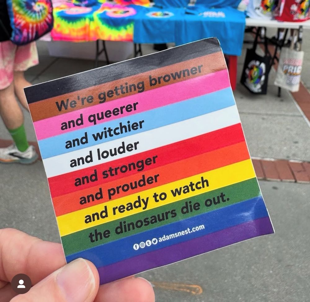 Someone holding a square card with the pride progress flag colours saying:
We’re getting browner
and queerer
and witchier 
and louder
and stronger 
and prouder
and ready to watch
the dinosaurs die out

Adamsnest.com