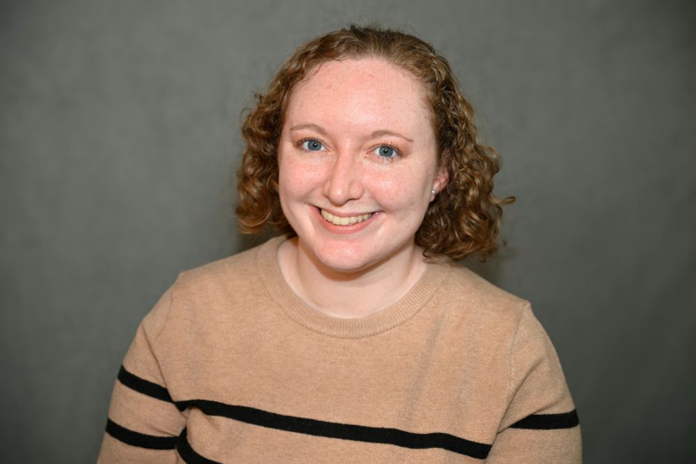 Woman in tan sweater with black stripes smiling