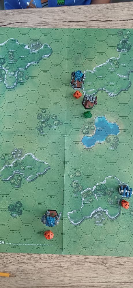 Photo: an overview of the battlefield with the four mechs placed across from each other in teams of 2. Movement dice are visible.