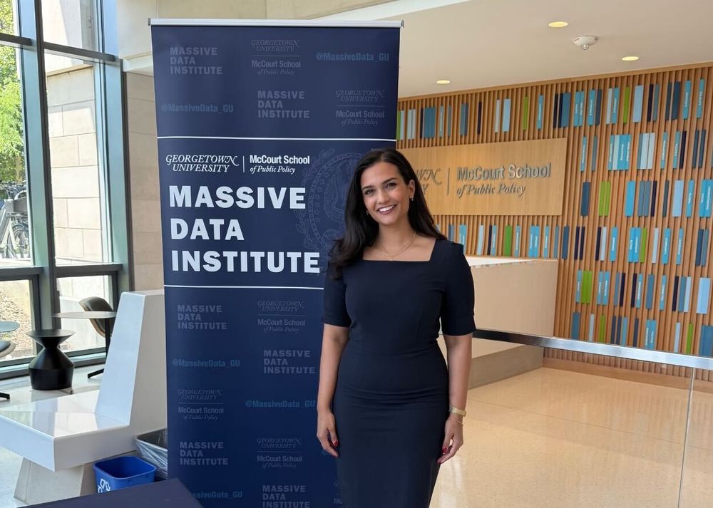 A photo of Shreya Singh Hernández in front of event signage at the Administrative Data Research Conference.