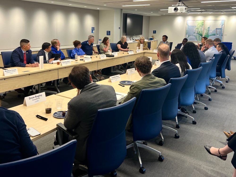A photo of roundtable participants seated around a conference table.