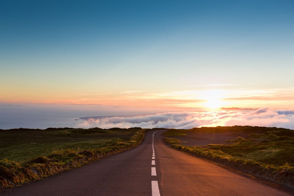 A photograph of a sunrise over a winding road.