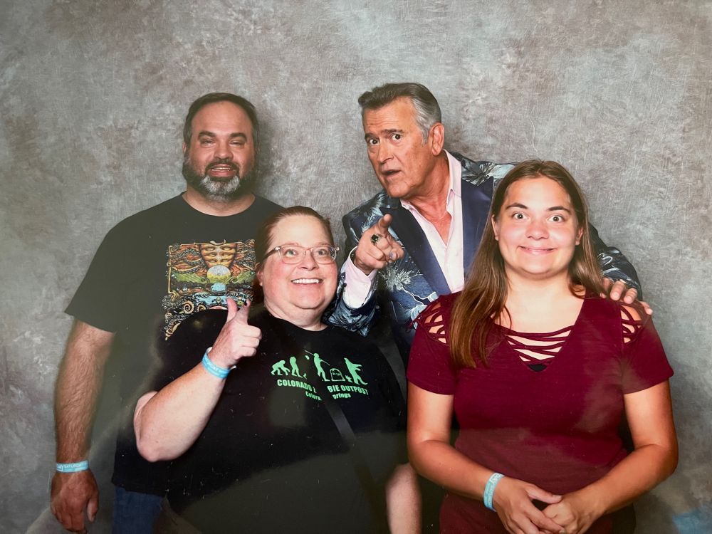 Tom, Kari, and Natasha Wolfe with Bruce Campbell pointing at the camera.