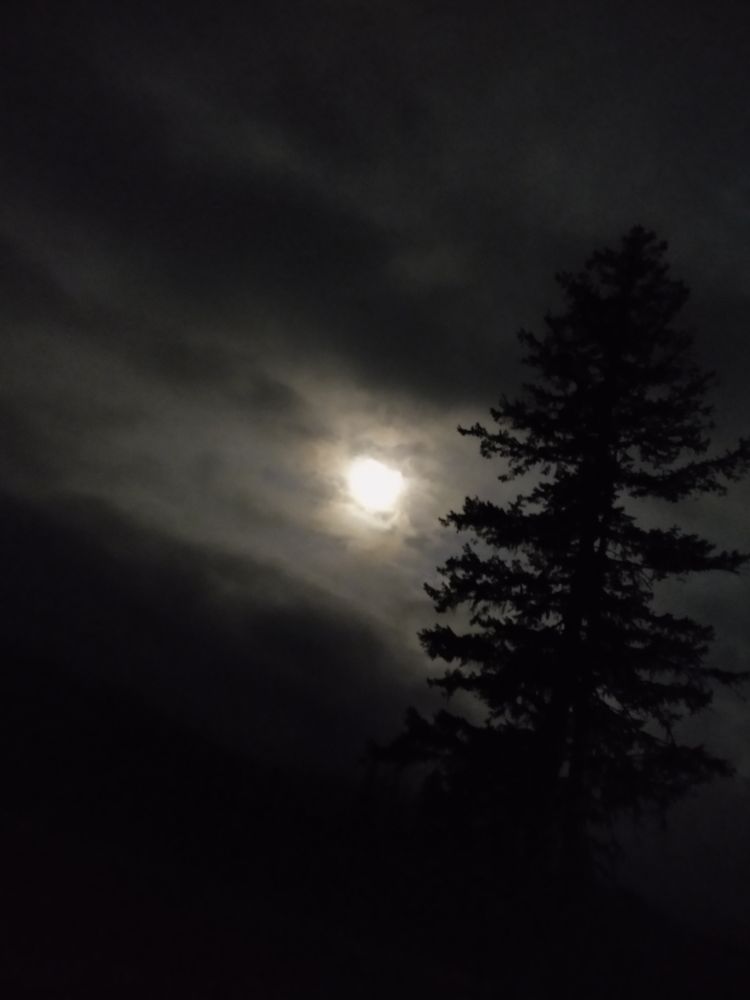 full moon peeking through a halo of cloudz
