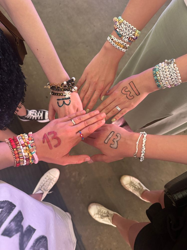 Hands with 13s painted onto them and friendship bracelets on the wrists