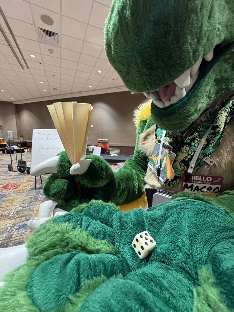A dragon holds a Dice Game paper fan and a 6-sided die. Is the fan small, or the dragon big?