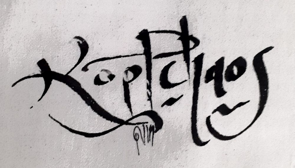 Leicht schwungvoll verspieltes Schriftbild des Wortes Kopfchaos mit schwarzer Farbe auf grau-weißem und gefiltertem Untergrund. 