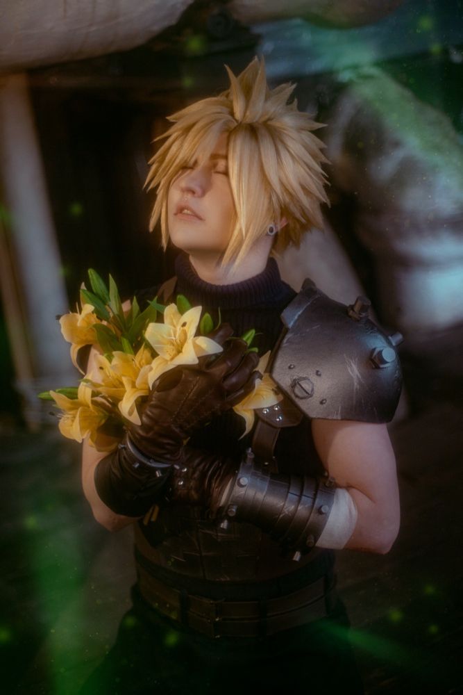 Cloud cosplayer holds flowers to his chest with his eyes closed. 