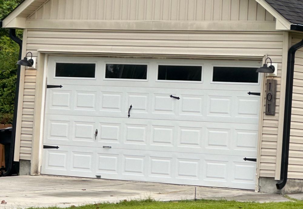 A garage door with four different handles installed at seemingly random heights and angles
