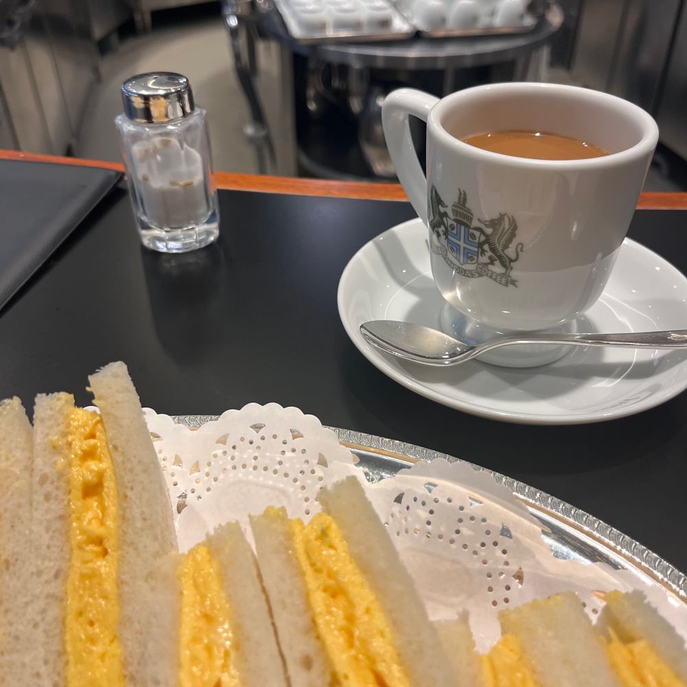 手前にオムレツサンド、奥に白いカップアンドソーサーに入ったミルクコーヒー