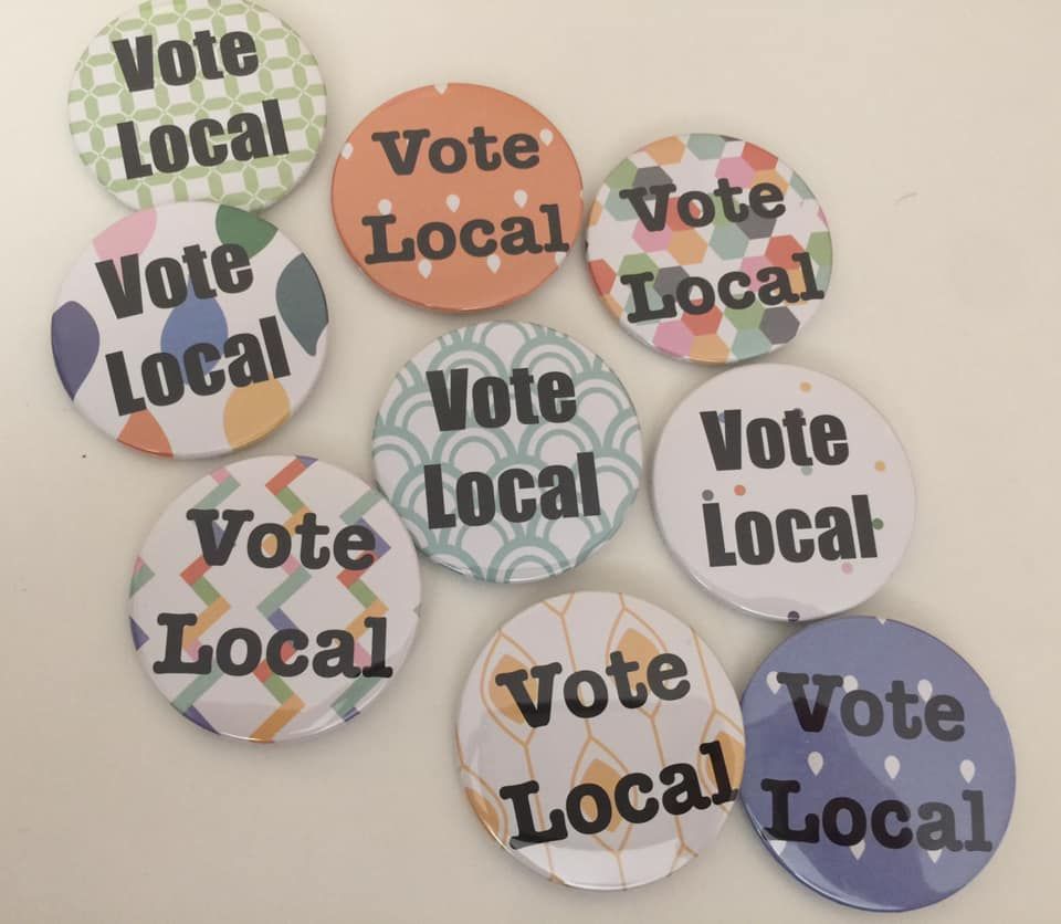 Photo of campaign buttons saying "Vote Local"