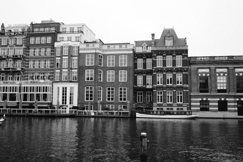 A row of typical thin houses in Amsterdam. In front of them is a canal.