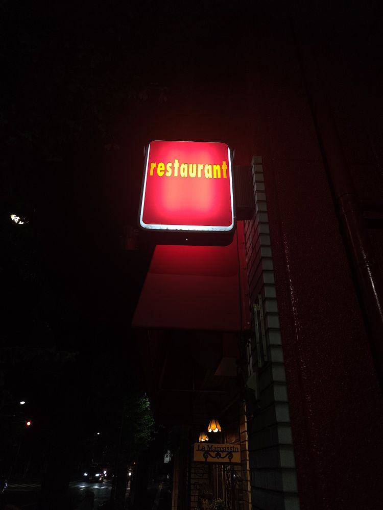 A red, lighted sign sticking out of the side of a building that just says "restaurant."