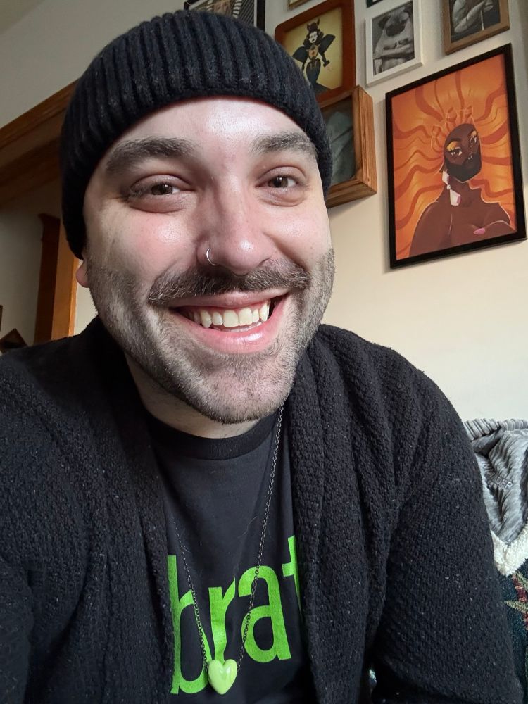 Me in a brat t shirt, a black cardigan, and a black beanie