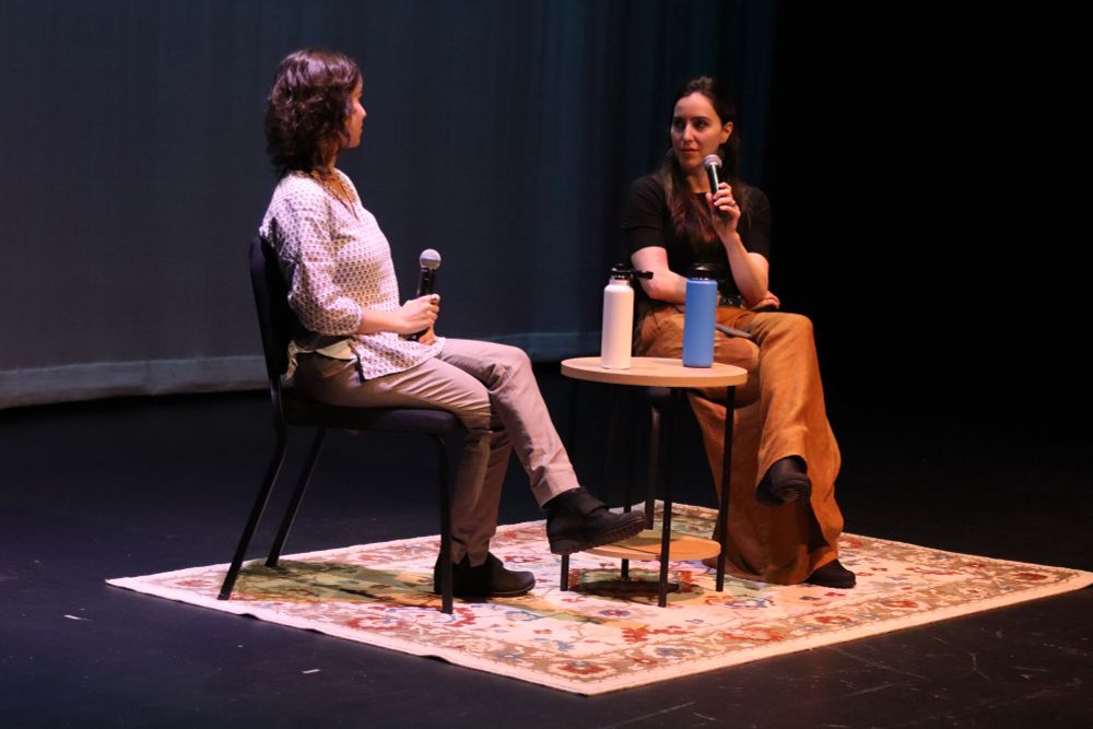 Two people sitting in chairs on stage for q&a 