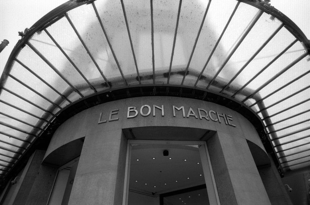 A wide-angle black and white photograph of the entrance to Le Bon Marché, Paris’s historic department store. Taken with the Minolta CLE and Voigtländer 21mm f/4 Color-Skopar on Kentmere Pan 100, developed in T-Max (1:4).