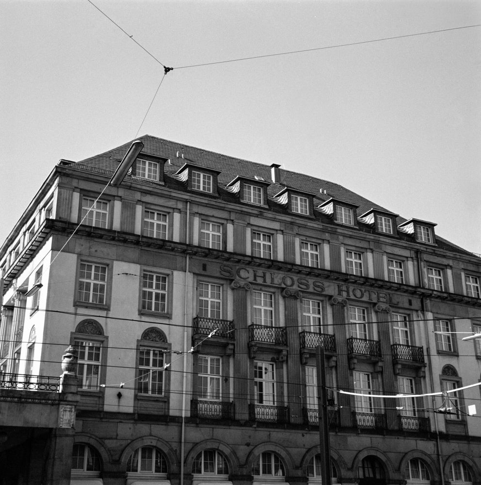  Black and white photo of the Schloss Hotel, a grand multi-story building with arched windows, dormers, and ornate balconies, intersected by overhead tram wires; shot on Ilford HP5+ film with a Voigtländer Perkeo II and 80mm f/3.5 Color-Skopar lens, developed in XTOL 1:1.