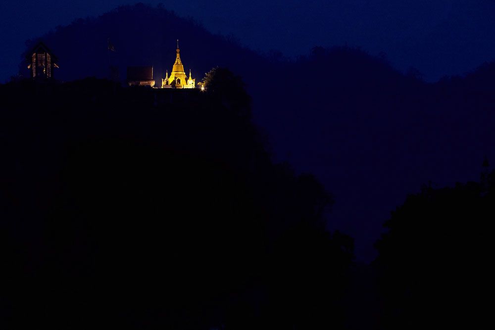 A chedi at Wat Ka Nun sits on a limestone cliff as evening falls over the little town of Thong Pa Pum, Thailand.