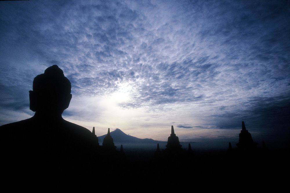 Dawn at Borobudur in Central Java, Indonesia. Borobudur is the largest Buddhist monument in the world.  The ever grumpy volcano, Gunung Merapi, rumbles in the distance.