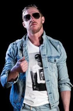 Orange Cassidy giving a half-heated thumbs-up. He’s wearing dark sunglasses, a denim jacket, and a T-shirt of himself wearing a T-shirt of himself