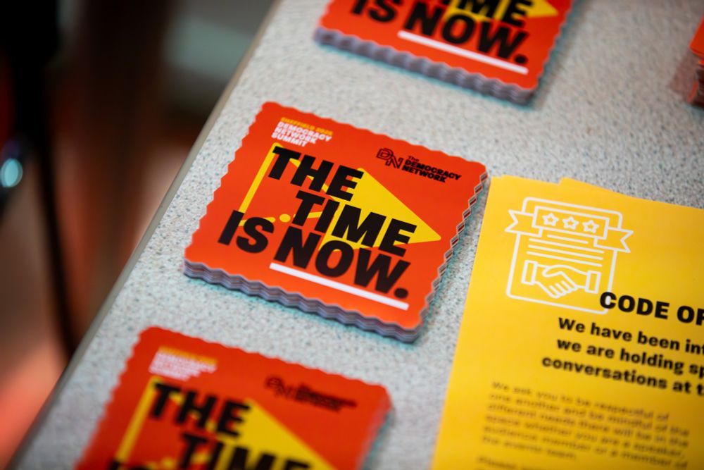 Stickers can be seen lined up on a table. They claim the "Time is now."