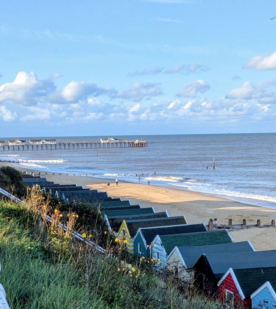 Photo of a Suffolk coast, with beach huts and a pier in the distance 