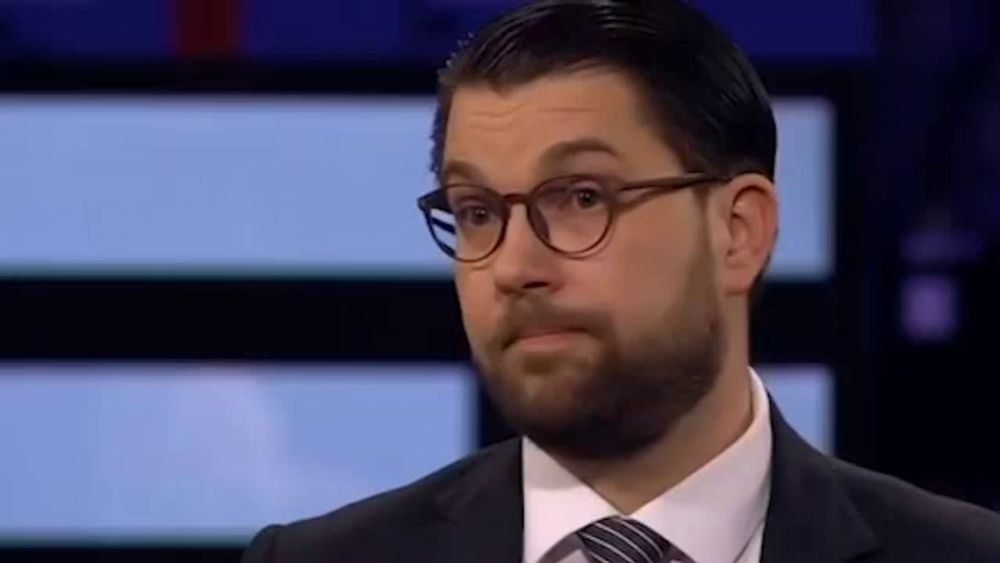 a man with a beard wearing glasses and a suit and tie is making a funny face .