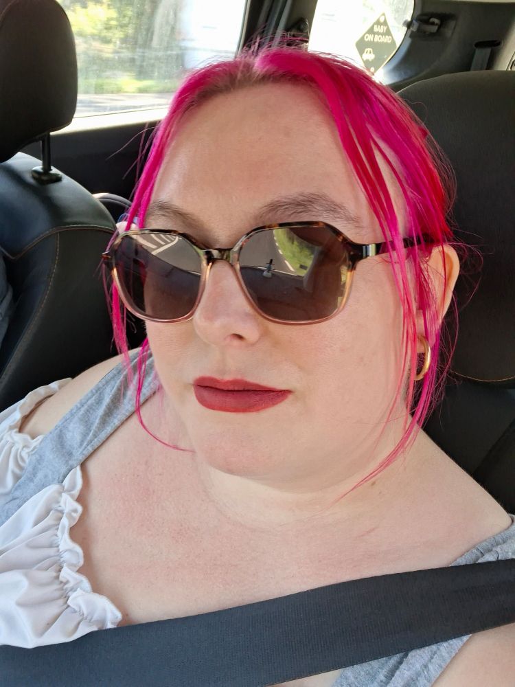 Photo de moi dans la voiture (toujours) maquillée avec les cheveux roses.