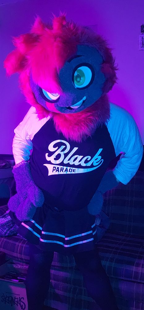 A furry alien dressed up in a black parade shirt and black skirt 