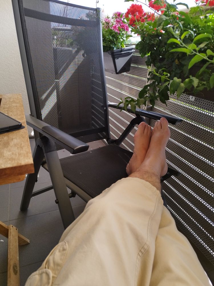 Meine Beine mit nackten Füßen auf einen Stuhl abgelegt auf dem Balkon 