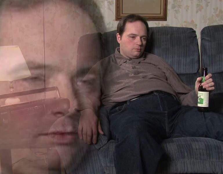 rich evans sitting on the couch, blankly staring off into space while holding a beer.