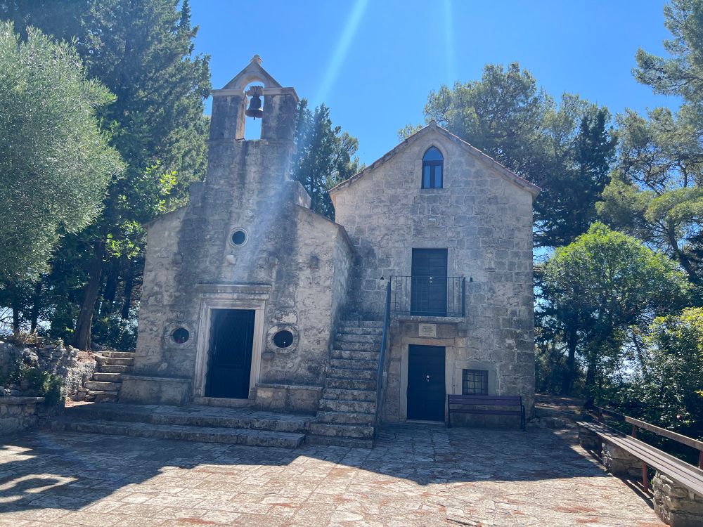 Front of the small church nestled in a grove of trees. 