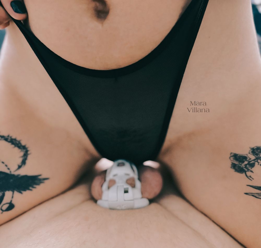 Close up of Mara Villana straddling her caged submissive in sheer black panties 