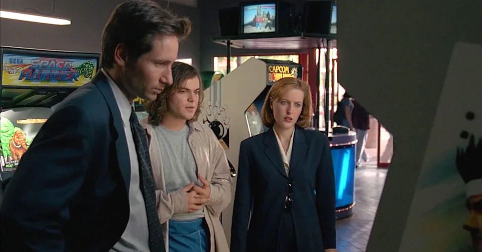 A young, long-haired Jack Black standing between Gillian Anderson and David Duchovney in the X-Files episode "D.P.O."