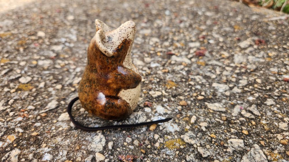 Small brown and cream ceramic mouse with a leather tail.