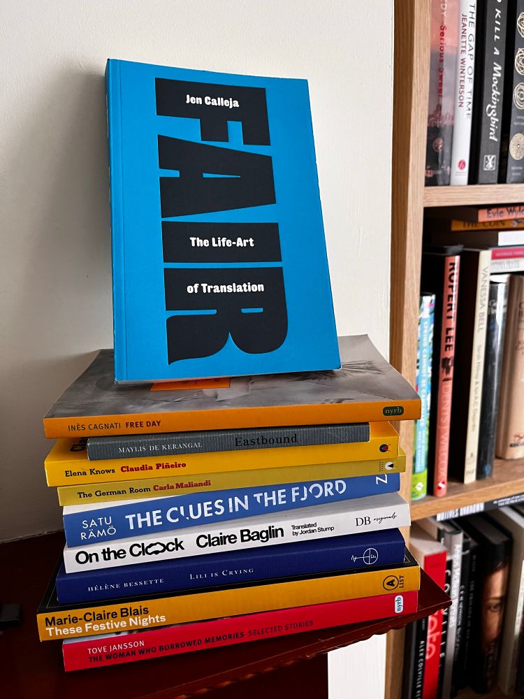A pile of books on a mantel piece, all by women, all in translation. On top is a copy of Jen Calleja's Fair: The Life-Art of Translation. In the pile are books by Inès Cagnati, Maylis de Kerengal, Claudia Piñiero, Carla Mallandi, Satu Rämo, Claire Bagun, Hélène Bessette, Marie-Claire Blais and Tove Jansson. 