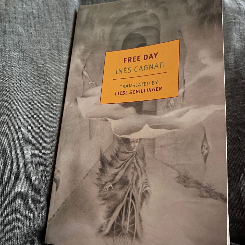 Photo of the NYRB Classics edition of Free Day by Inès Cagnati, translated by Liesel Schillinger. The cover shows a black and white drawing of a haunted looking woman on a bicycle through a surreal landscape of ghosts and tunnels. 