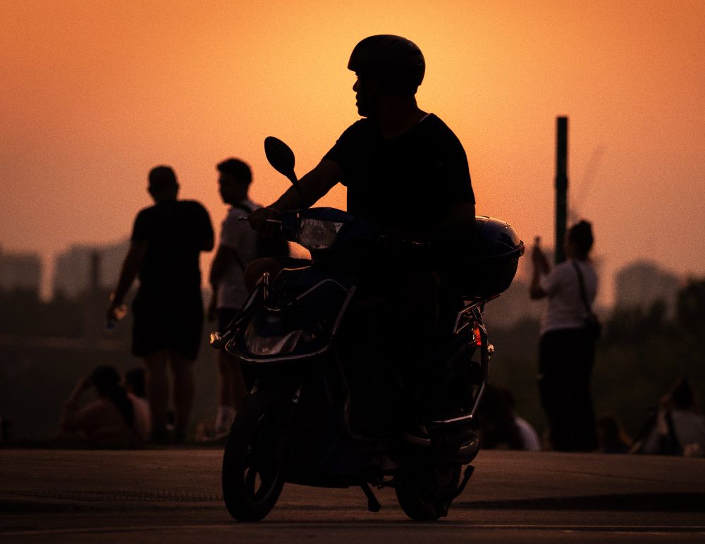 A picture of a person riding an e-bike at sunset.