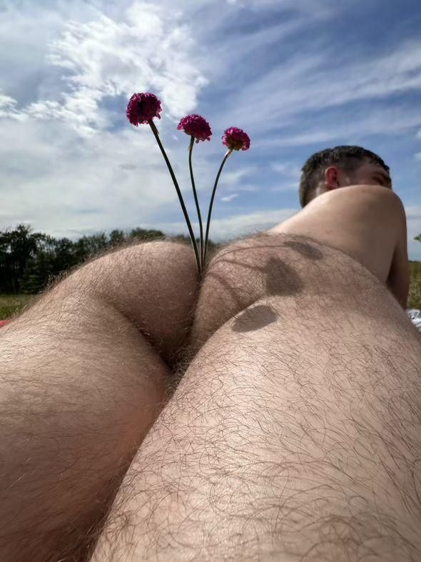 Nude tanning, butt showing with three flowers being held in the butt crack