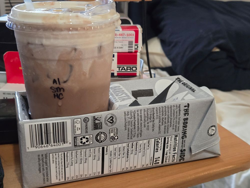 An iced hot chocolate sitting in a drink tray made from a carton of oat milk.