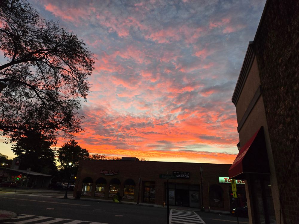 Sunrise over a suburban street, the clouds are bright red and orange.